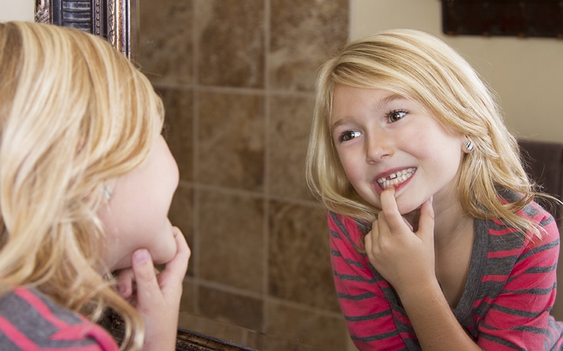 girl looking at missing tooth