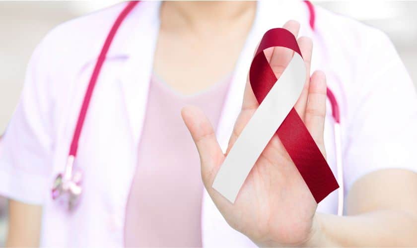 Healthcare professional holding red ribbon symbol for awareness campaign in medical setting.