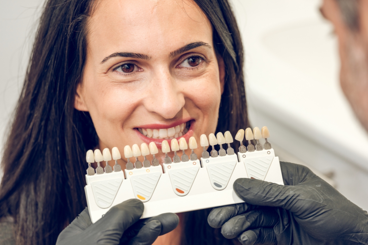 Patient comparing porcelain veneer shades during cosmetic dental consult