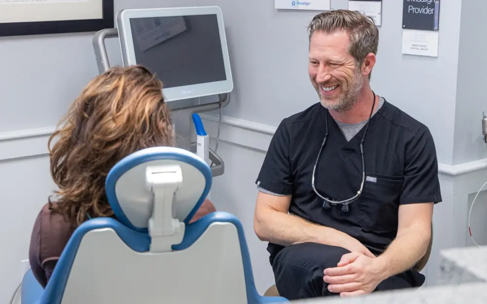 Orthodontist smiling and talking with a patient seated in a dental chair